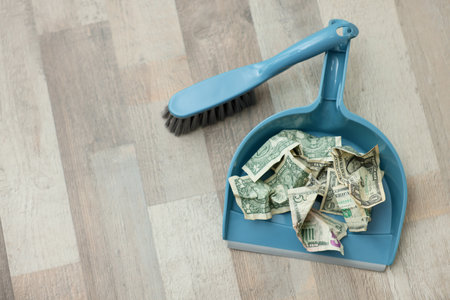Dollar banknotes, dustpan and broom on floor background, above view. Space for textの写真素材