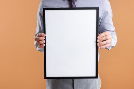 Man with blank diploma frame on pale orange background, closeup. Mockup for designの写真素材