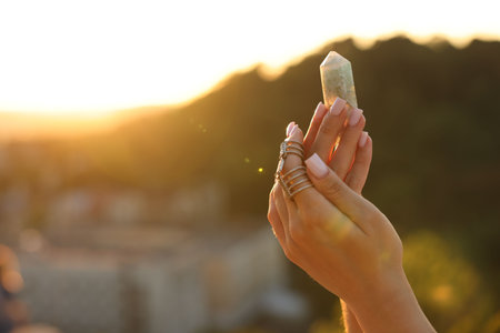 Woman meditating with crystal to heal or restore her aura outdoors, closeup. Space for textの写真素材