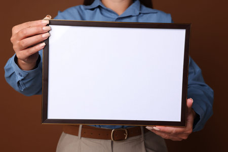 Woman with blank diploma frame on brown background, closeup. Mockup for design