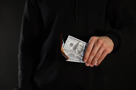 Man burning dollar banknotes on black background, closeupの写真素材