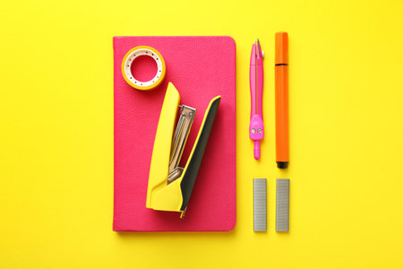 Stapler and other stationery on yellow background, flat layの写真素材