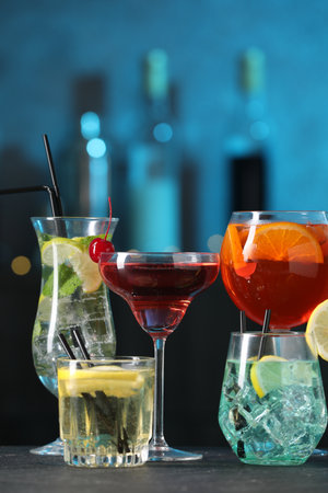 Glasses of tasty cocktails on dark table against blurred backgroundの写真素材