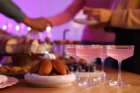 Glasses of cocktails and people with delicious desserts at buffet table, selective focusの写真素材