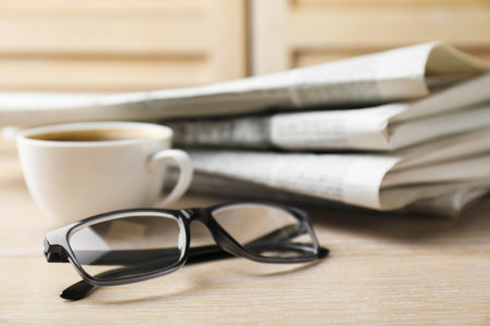 Stack of newspapers, coffee and glasses on wooden table, closeupの写真素材