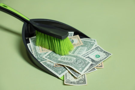 Dollar banknotes, dustpan and broom on green background, closeupの写真素材