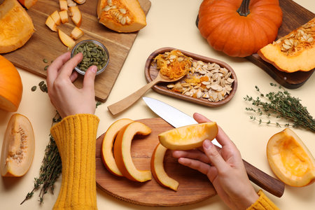 Woman with pumpkin pieces, seeds and thyme on beige background, top viewの写真素材
