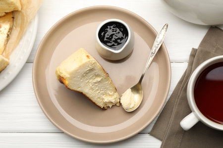 Piece of delicious cheesecake, chocolate sauce and tea on white wooden table, flat layの写真素材