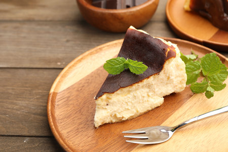 Piece of delicious Basque cheesecake with mint on wooden table, closeupの写真素材