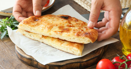 Woman with delicious Megrelian khachapuri at wooden table, closeup