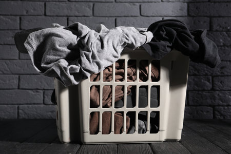 Laundry basket full of clothes on black wooden surfaceの写真素材