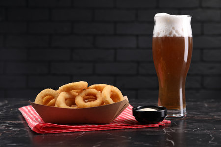 Fried squid rings with sauce and beer served on black marble table. Space for textの写真素材