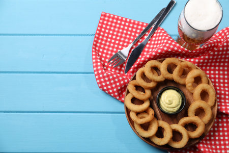 Fried squid rings with sauce served on blue wooden table, flat lay. Space for text