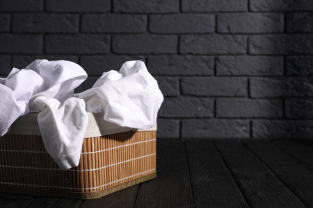 Basket full of clothes on black wooden surface. Space for textの写真素材