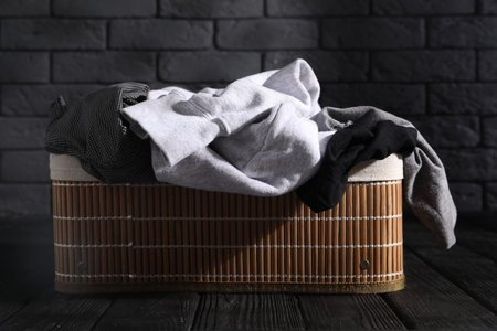 Laundry basket full of clothes on black wooden surfaceの写真素材