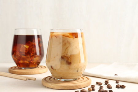 Tasty iced coffee with milk and beans on white tableの写真素材