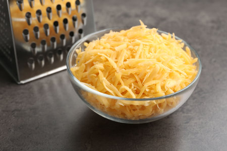 Grated cheese and grater on gray table, closeupの写真素材