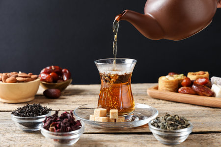 Pouring freshly brewed Turkish tea into glass at wooden table, closeupの写真素材