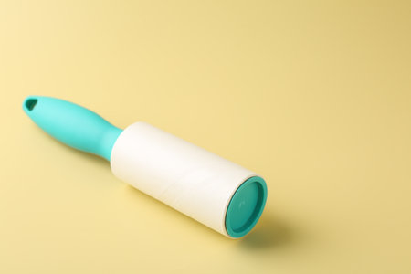 One lint roller on yellow background, closeup. Space for textの写真素材