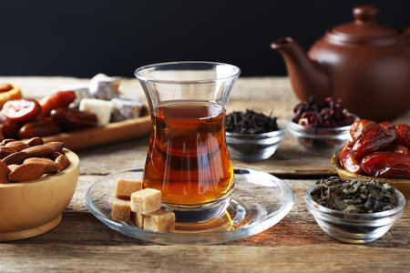 Traditional Turkish tea, dry leaves, sugar and sweets on wooden table, closeupの写真素材