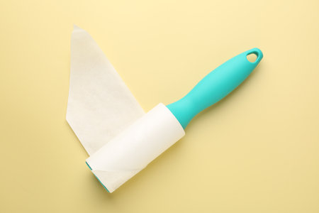 Lint roller with used sticky tape on yellow background, top viewの写真素材