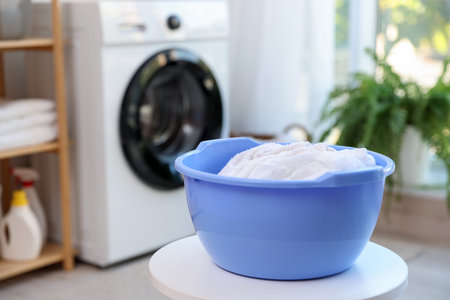 Plastic basin with laundry on white table in bathroom, closeup. Space for textの写真素材