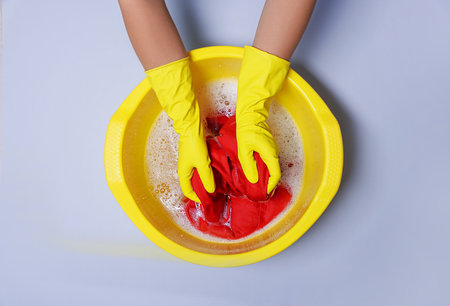 Woman washing clothes in plastic basin on light gray background, top viewの写真素材