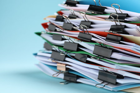 Many folders with documents and binder clips on light blue background, closeupの写真素材
