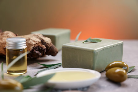 Handmade soap bars, olives, green leaves and oil on gray table, closeupの写真素材