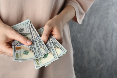 Alimony. Woman with dollar banknotes on gray background, closeup. Space for textの写真素材