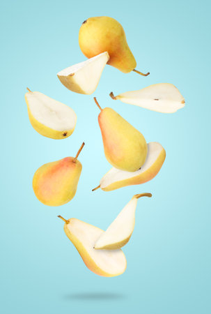 Many fresh pears falling on light blue backgroundの写真素材