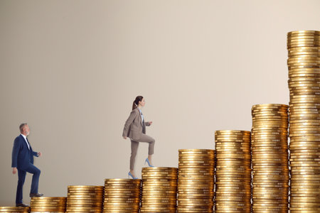 Way to wealth. Man and woman going up on stacks of coins against beige gray backgroundの写真素材