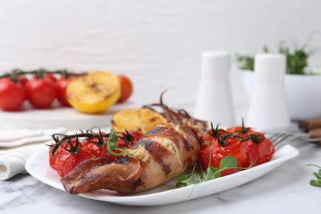 Tasty stuffed squid, microgreens, lemon and tomatoes on white marble table, closeup