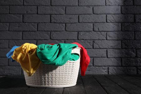 Laundry basket full of clothes on black wooden surface. Space for textの写真素材