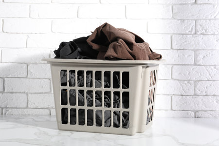 Laundry basket full of clothes on white marble surfaceの写真素材