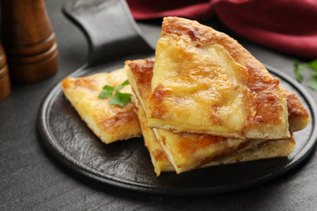 Pieces of delicious Megrelian khachapuri on black table, closeupの写真素材