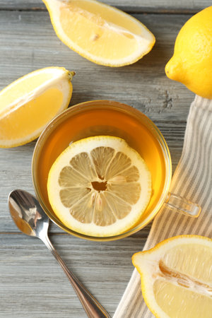 Aromatic tea in cup, lemons and spoon on wooden table, flat layの写真素材