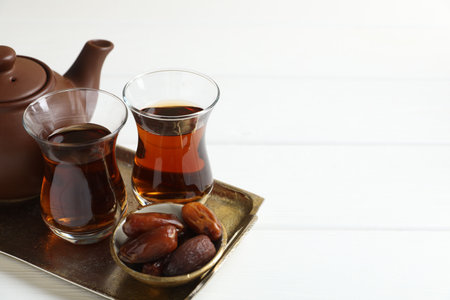 Traditional Turkish tea and dates on white wooden table, closeup. Space for textの写真素材