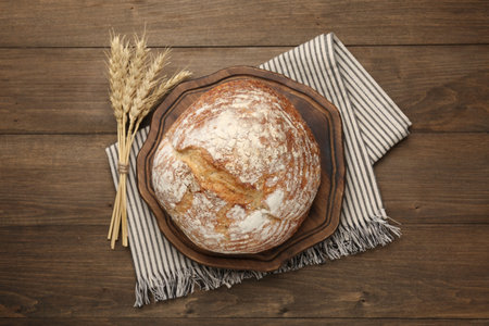 Loaf of fresh bread on wooden table, flat lay