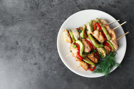Tasty skewers with chicken, vegetables, dill and green onion on gray table, top view. Space for textの写真素材