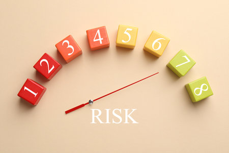 Arrow indicating level of risk on scale made of colorful cubes on beige background, top viewの写真素材