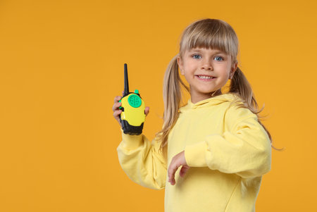 Little girl with walkie talkie toy on yellow background, space for textの写真素材