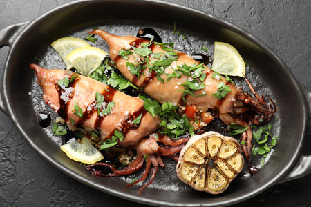 Tasty cooked squids with sauce and garlic in dish on black table, top viewの写真素材
