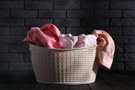 Laundry basket full of clothes on black wooden surfaceの写真素材