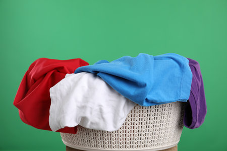 Laundry basket with colorful clothes on green backgroundの写真素材