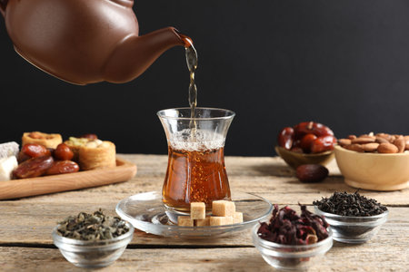 Pouring freshly brewed Turkish tea into glass at wooden table, closeupの写真素材