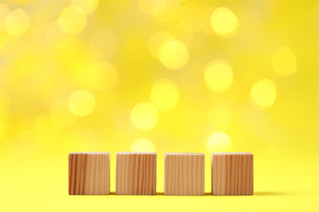 Blank wooden cubes on yellow background, closeup. Bokeh effectの写真素材