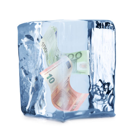 Bills in ice cube on white background. Frozen moneyの写真素材