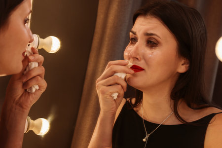 Woman with smeared mascara in dress near mirror indoorsの写真素材