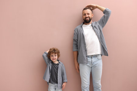 Father and son measuring their heights near beige wall indoorsの写真素材